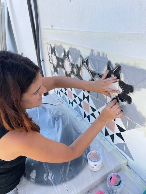 Gema pintando el zócalo de la cocina de exterior con esponja